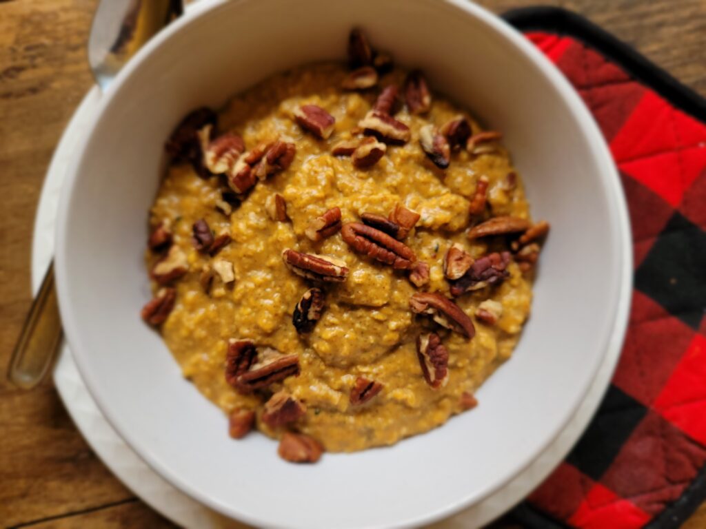 Low sugar pumpkin spice oatmeal served in a white bowl with spoon