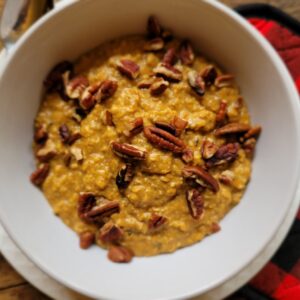 Low sugar pumpkin spice oatmeal served in a white bowl with spoon